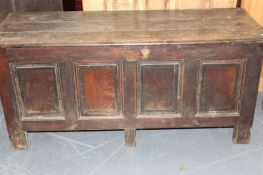 An early 18th Century oak coffer, with plank top over four panel front, on stile feet