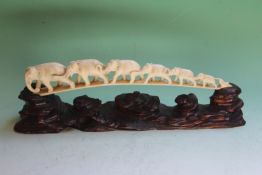 An early 20th Century Japanese carved ivory elephant train, on carved hardwood stand, 34cm long over