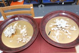 A pair of Japanese circular wall plaques, carved flowers with lacquer surrounds, 46cm diameter