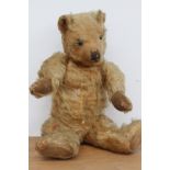 A vintage plush teddy bear with jointed arms and legs