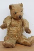 A vintage plush teddy bear with jointed arms and legs