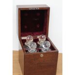 An early 20th Century oak cased four bottle tantalus, containing four cut glass decanters