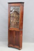 A George III mahogany floor standing cabinet in two parts, the upper with single glazed panel door