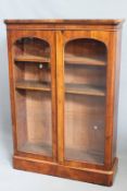 A Victorian walnut bookcase, with twin arch top glazed panel doors enclosing adjustable shelving, on