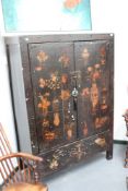 A Chinese lacquer floor standing two door cupboard, with polychrome symbol and floral decoration,