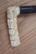 A Japanese carved ivory cane handle, signed and decorated with noh marks, mounted on a hardwood