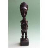 A carved stylized tribal female standing figure, possibly African, 31cm high.