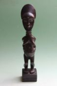 A carved stylized tribal female standing figure, possibly African, 31cm high.