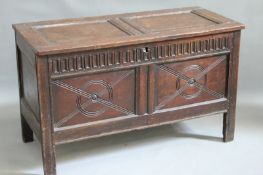 An 18th Century oak coffer, the twin panel top over conforming front with line and roundel