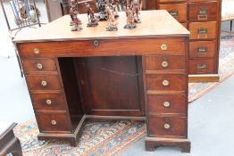 An unusual early 19th Century mahogany kneehole desk/writing cabinet with hinged top, two banks of