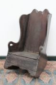 An antique oak rustic child's rocking/potty chair, with shaped back and arms