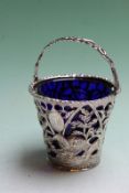 A George III silver sugar basket with Bristol blue glass liner, repousse cut card decoration, London