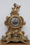 A French bronze Rococo style mantel clock, with putto playing a lyre atop scroll case with foliate