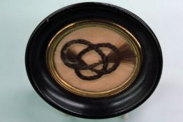 A plaited lock of hair. Reputedly from Admiral William Bligh. Ebonized oval moulded frame.