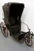 A 19th Century bath chair in black and red livery, button upholstered seat and folding hood. Steel