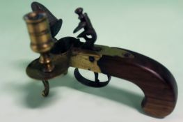 A good copy of a brass flintlock tinder lighter, scroll engraved frame with lyre stand and turned