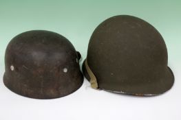 A WWII German paratroopers helmet with lining and straps together with an American helmet.