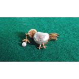 A chick brooch set with pearls.