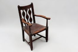 An Arts and Crafts oak armchair, with shaped slatback and arms over close nailed leather seat.