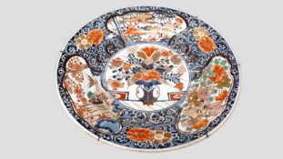An Japanese Imari dish the centre painted with a vase of chrysanthemums and peonies, the border with