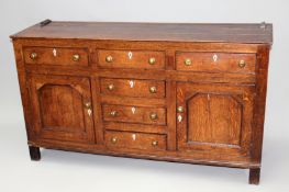 An antique country oak dresser base. Fitted with three frieze drawers above two side cupboards