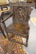 An antique carved oak Wainscot armchair. Figural back panel. Turned front legs, box stretchers.