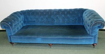 A large Victorian button back Chesterfield settee standing on triple, turned forelegs and castors.