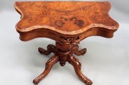 A Victorian walnut fold over card table. Moulded serpentine top over octagonal baluster column and