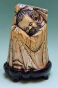 A Chinese ivory figure of a bearded man sleeping curled up with his head resting on his knees. Bears