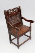 A 17th Century and later oak Wainscot armchair with scroll crest and carved back panel.