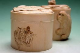 A Japanese carved ivory cylindrical lidded box carved with monkey designs to sides and cover. 7cm