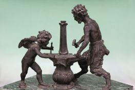 An antique bronze group of Cupid and a satyr blacksmith at the forge. Possibly Italian, shaped verde