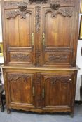 A French carved oak Provincial two part cabinet. Upper section with two shaped panel doors enclosing