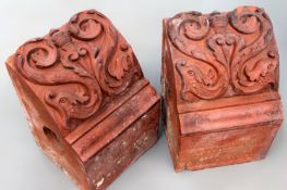 A pair of old terracotta architectural brackets with scroll decoration.