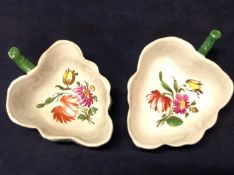 A pair of leaf shaped sauce-boats with hand painted sprays of wild flowers to the interiors.