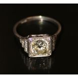 A platinum set single cushion shaped diamond ring with stepped diamond shoulder. Centre stone