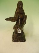 A Chinese bronze figure of a scholar holding ritual object. On carved wooden base. 26cm high.