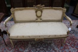 A carved and gilt Louis XVI style settee. Bird crest above shaped back and seat. Fluted tapered