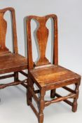 A pair of 18th Century oak hall chairs with shaped back splats and panel seats over turned legs