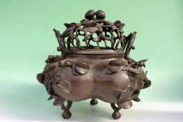 A Chinese bronze incense burner with pierced domed cover. Stylized branch side handles, flowering