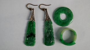 A pair of Chinese pierced jadeite drop earrings together with a ring and a circular boss. (4)