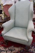 A George I style high wing back armchair. On shaped cabriole legs. United by stretchers.