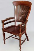 An interesting Arts and Crafts mahogany lathe back armchair, with shaped saddle feet over turned