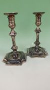 A pair of late Victorian silver table candlesticks with inverted square shaped bases, drip pan,