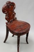 A Regency carved mahogany hall chair in the manner of Gillows, shaped back with central shield.