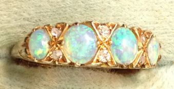 A gold four stone opal set ring with diamond points.