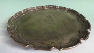 A silver salver with pie crust rim on three short scrolled feet and engraved presentation