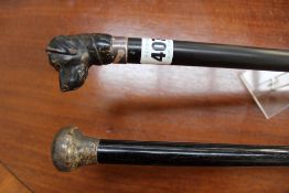 A late 19th Century ebony walking stick with carved hound dogs head finial and another ebony walking