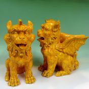 A pair of Burmantofts type yellow glazed pottery models of stylised seated dragons. 30cm high.