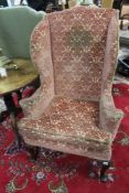 An antique country made elm Georgian style wing armchair. Cabriole legs end in pad feet.